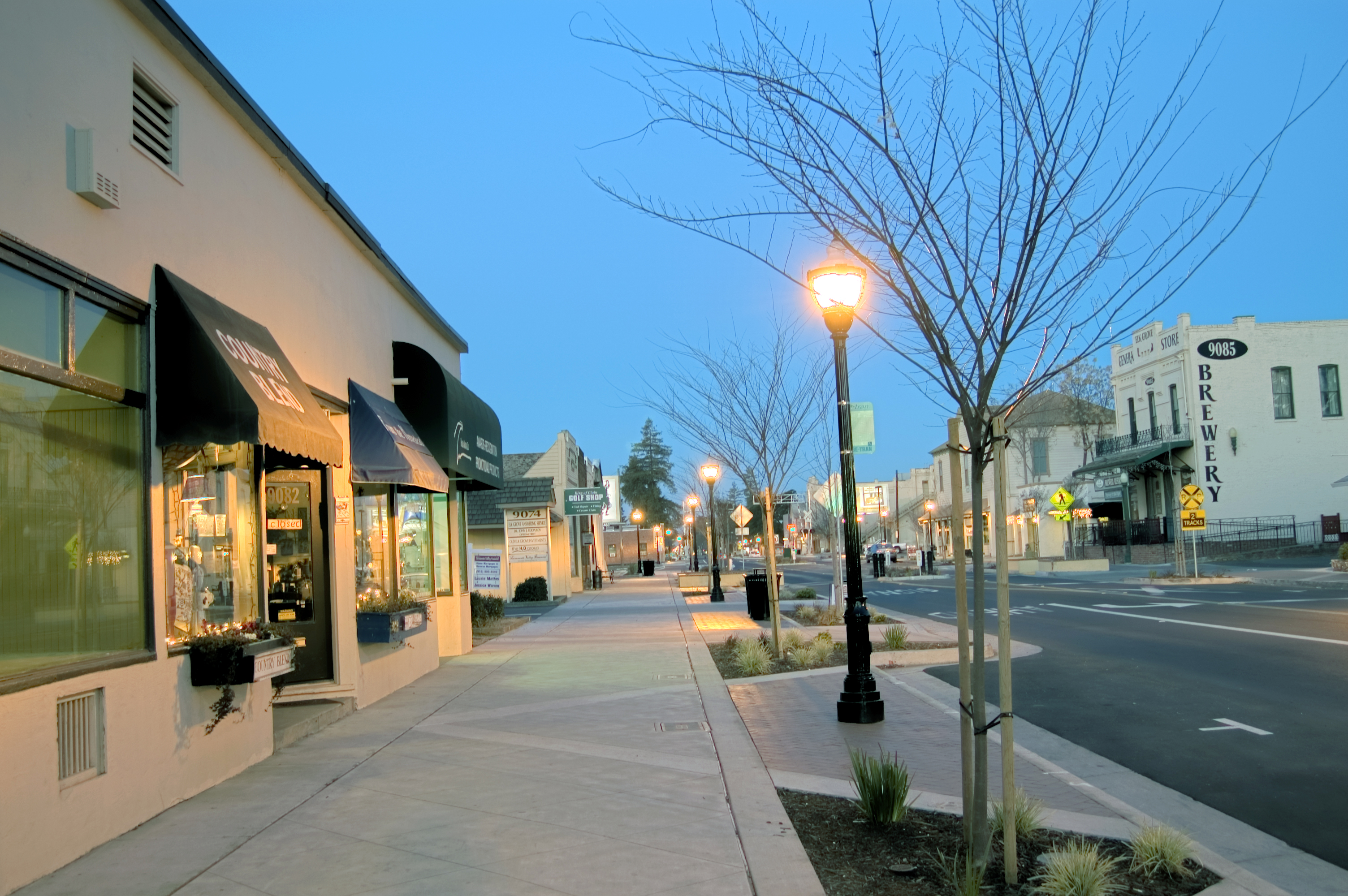 Old Town Elk Grove at dusk — historic main street, glowing lampposts, and the Elk Grove Brewery building